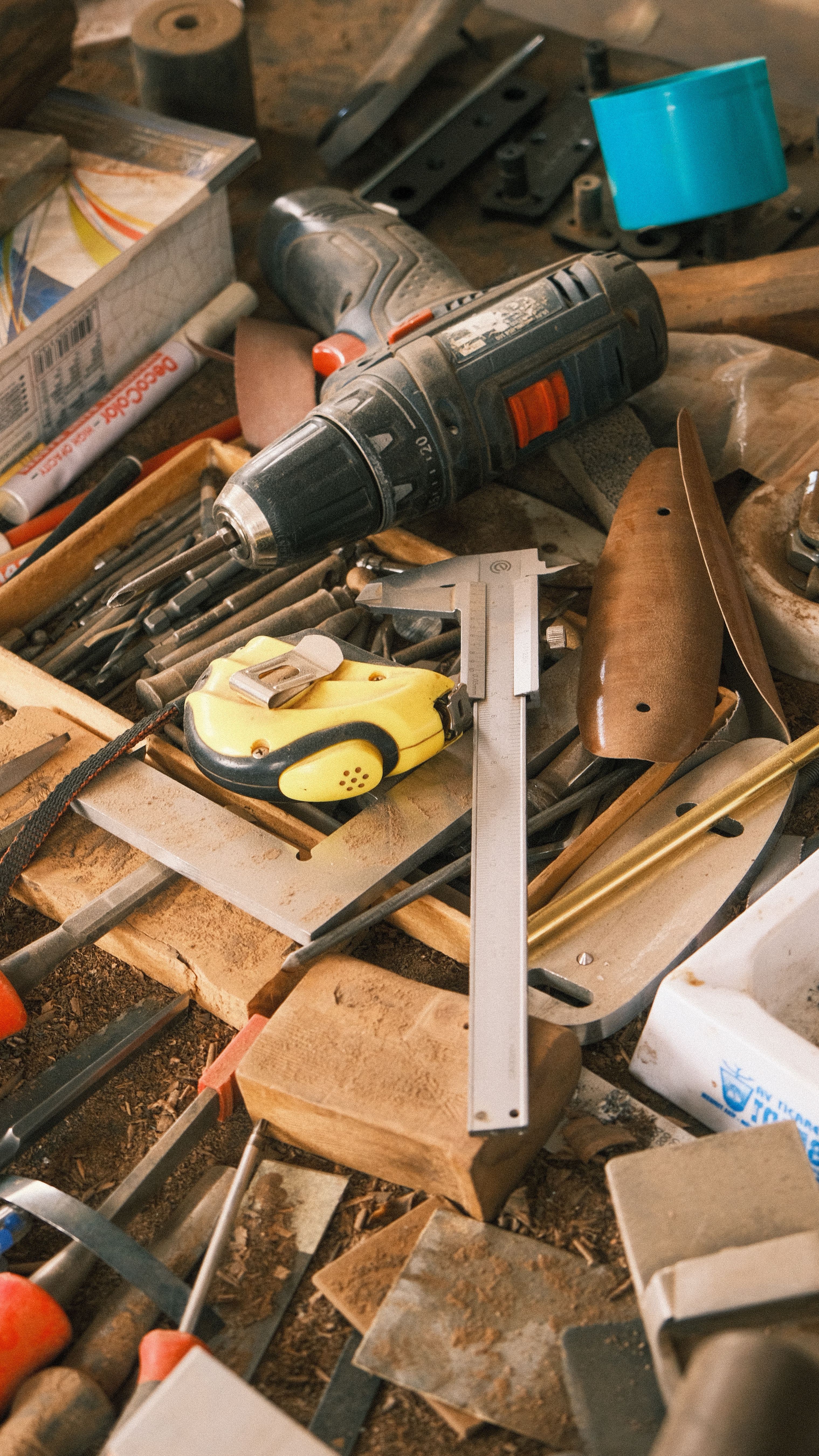 Overhead view of a gunsmith workbench covered with hand tools and wood stock blanks.