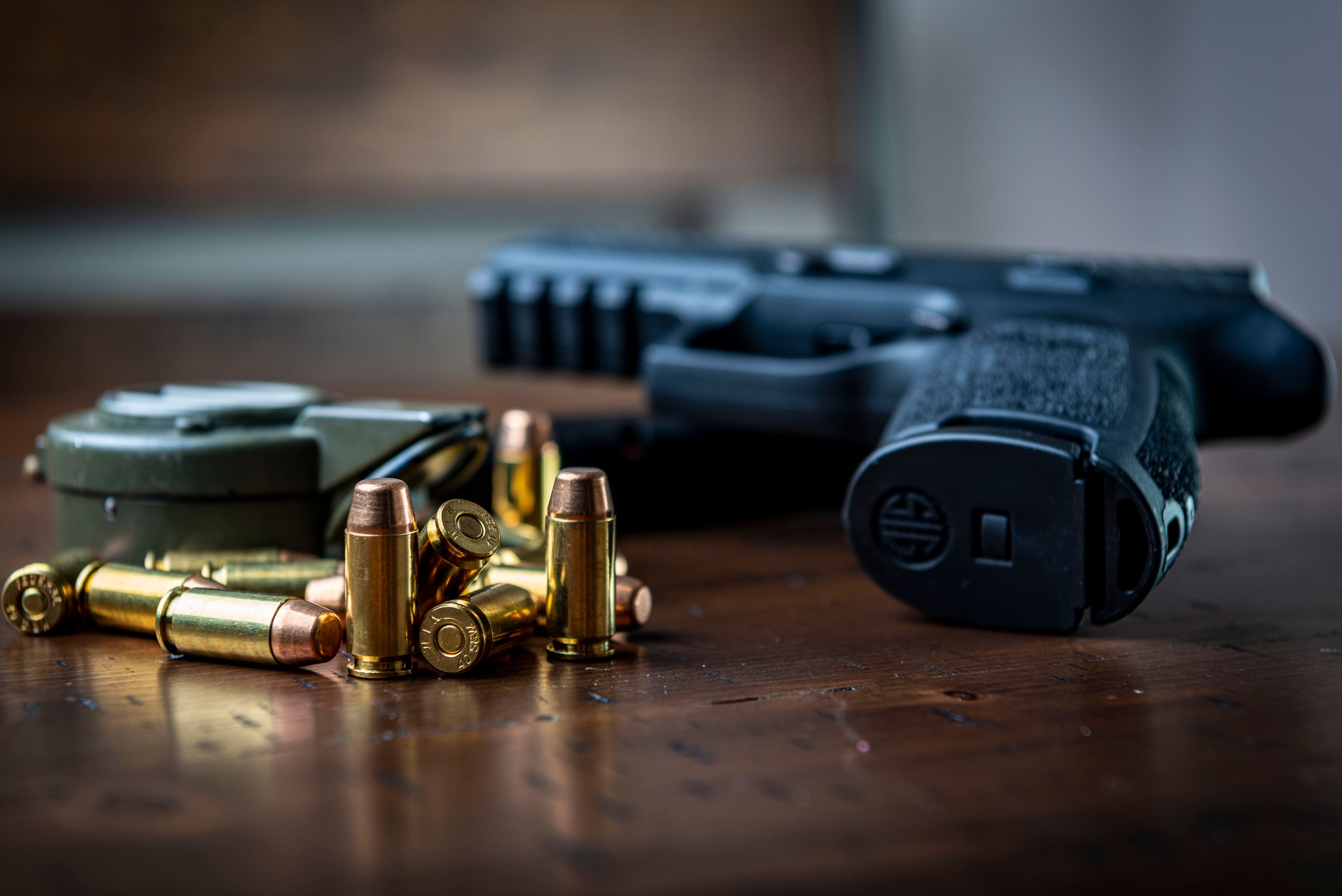 Pistol shown with loose ammunition and a magazine on a wooden table.