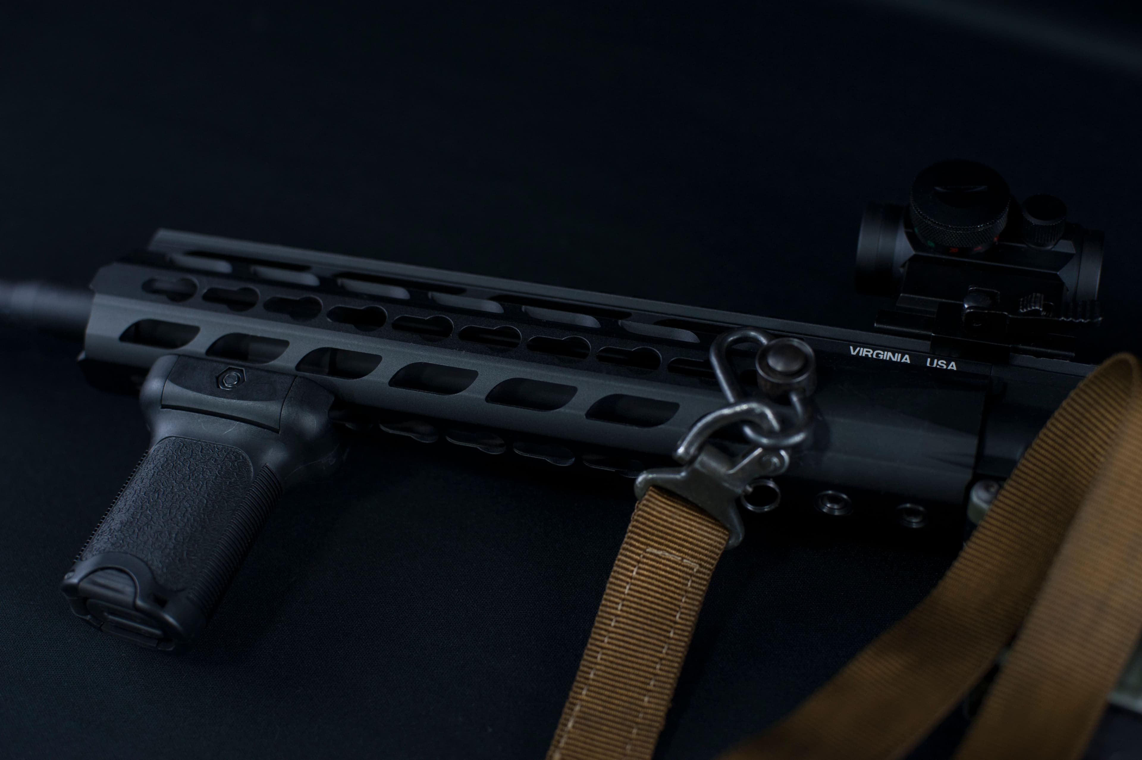 Close-up of a custom rifle handguard, optic, and tactical sling.